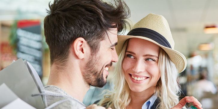 Happy young couple is flirting while shopping together in shopping mall